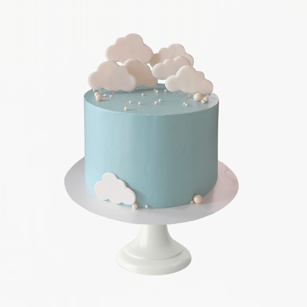 Light blue cake with cloud decorations on a white stand against a white background - children's birthday cake Sydney