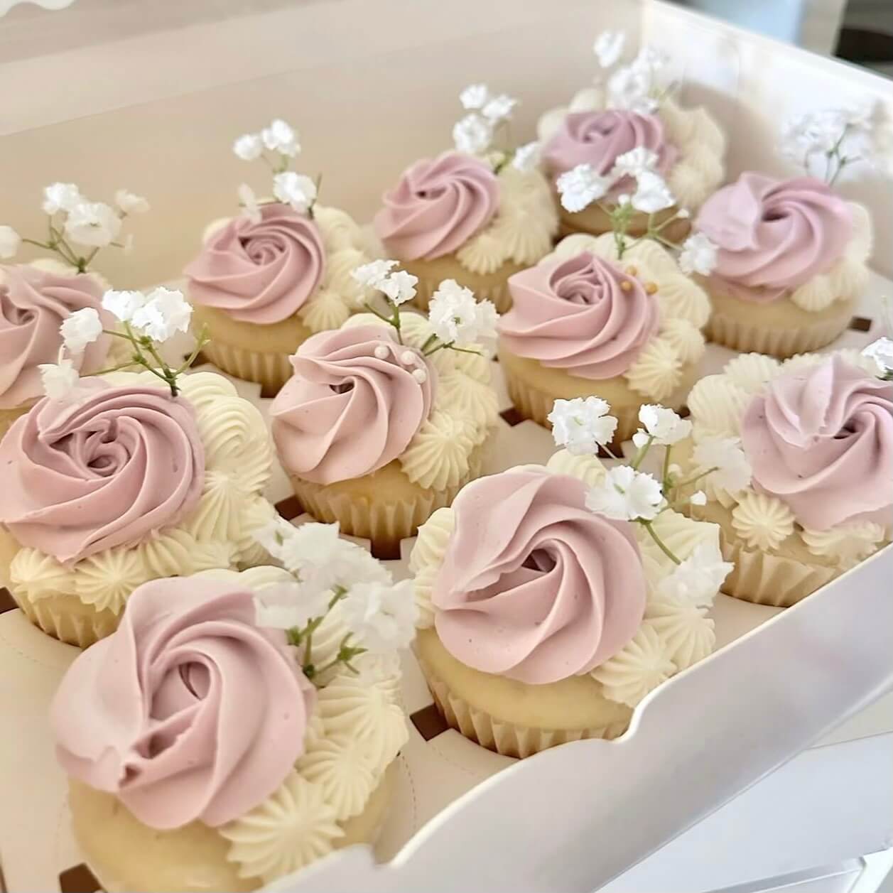 Cupcakes with pink and white frosting in a box