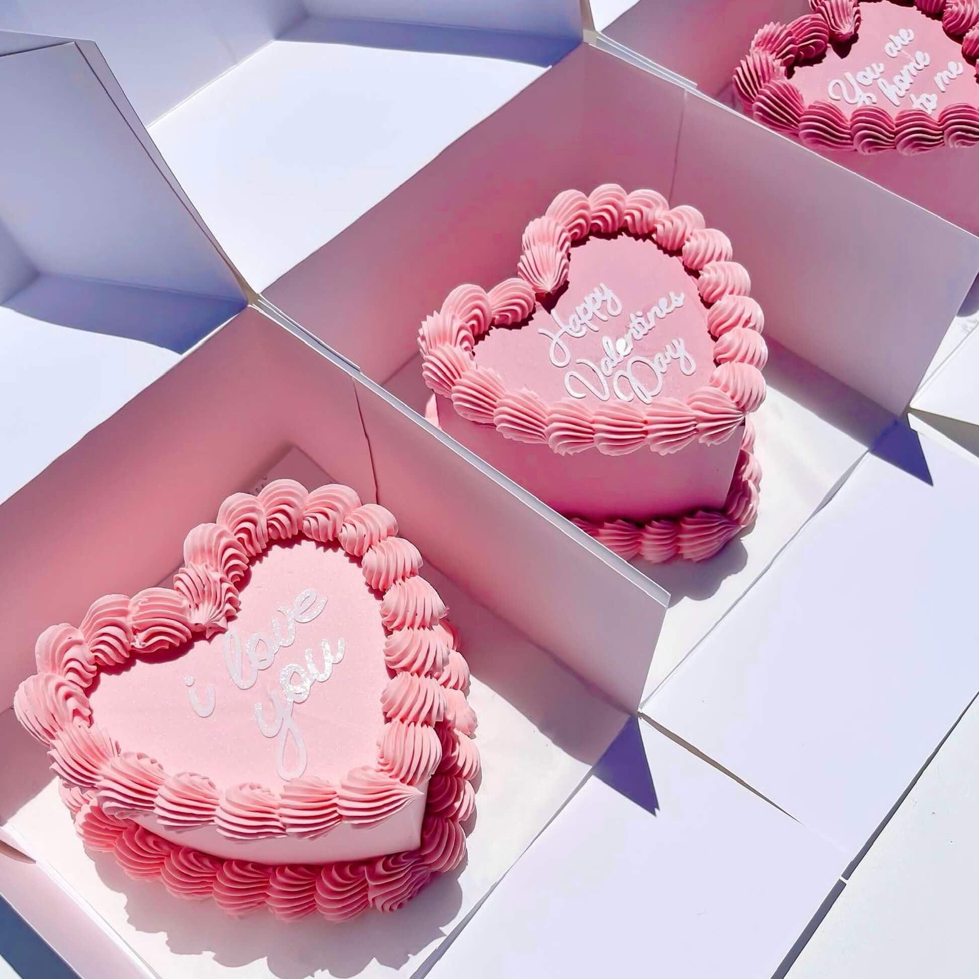 Heart-shaped pink cakes with 'Happy Valentine's Day' text on a white background