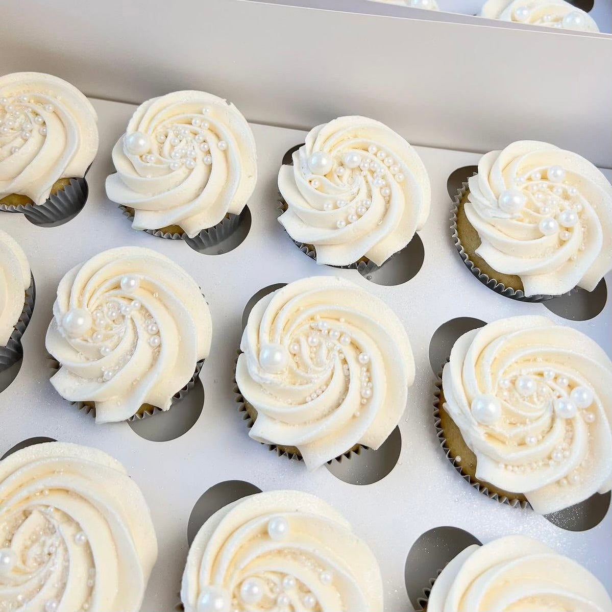 Box of cupcakes with white frosting and pearl decorations
