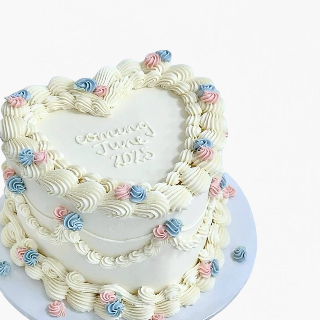 Heart-shaped cake with white frosting, pink and blue decorations on a white background - gender reveal cake Sydney