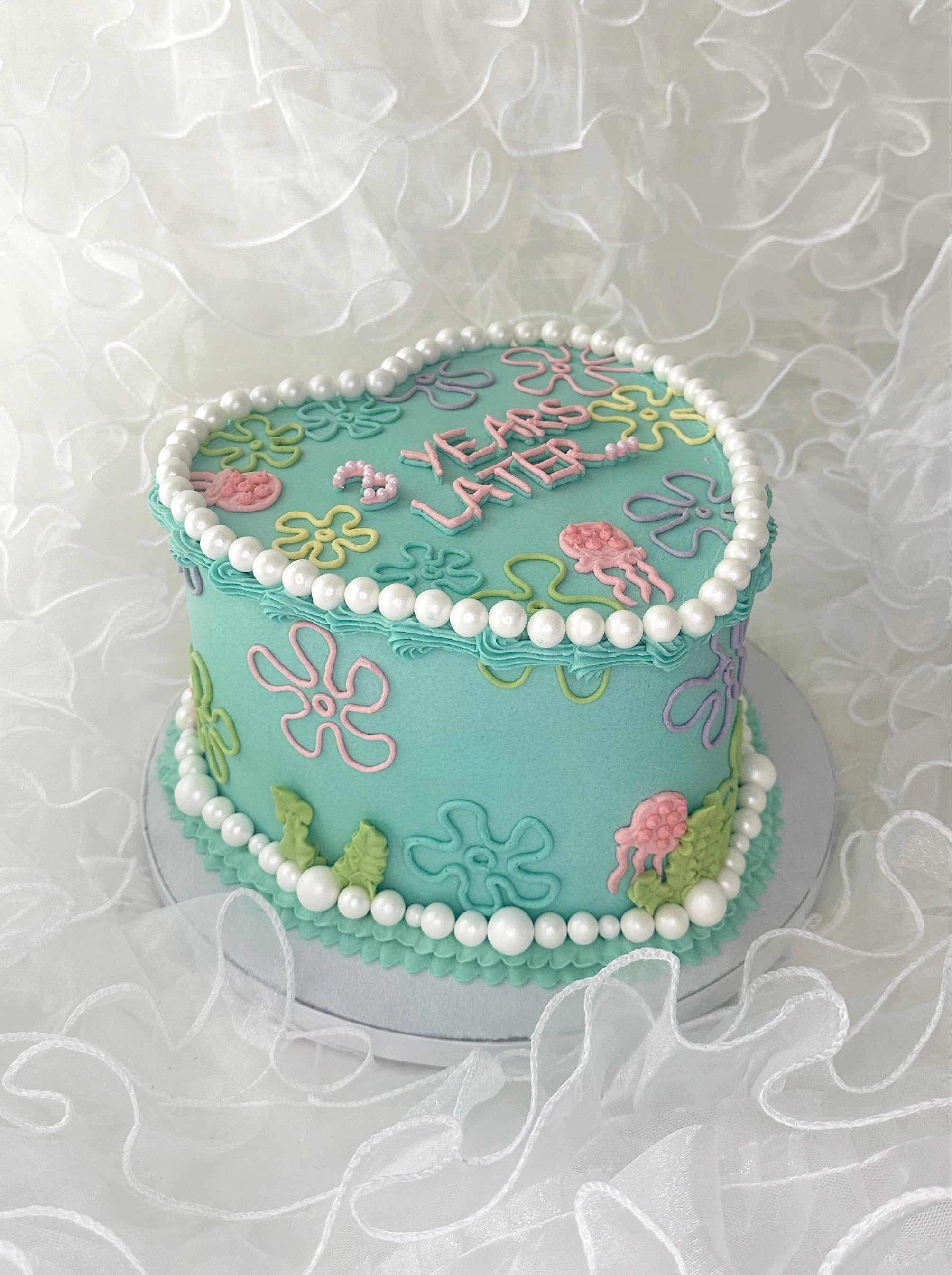 Teal graduation cake with floral designs and '10 Years Later' texr