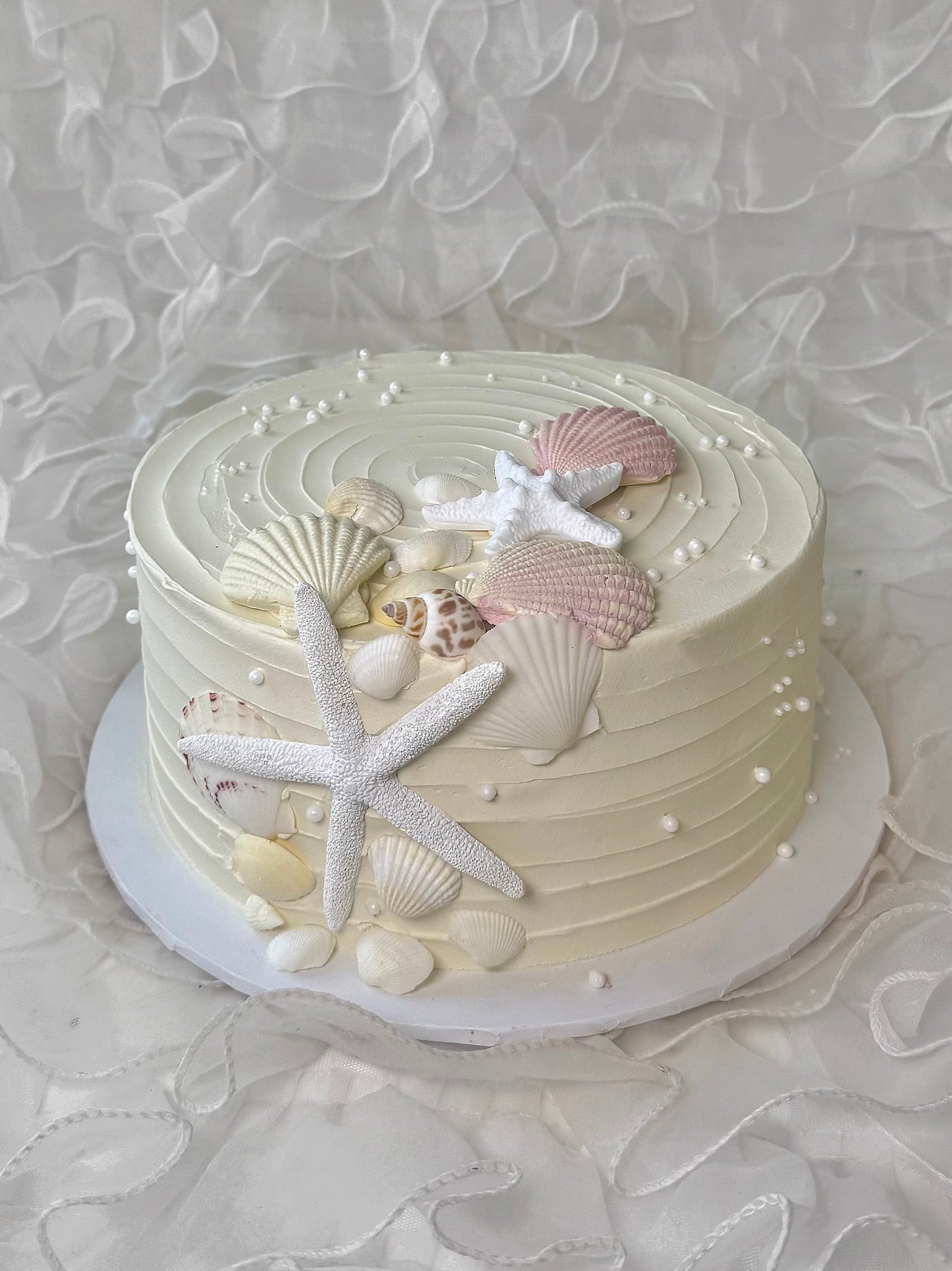 Decorative cake with seashells and starfish on a textured white background