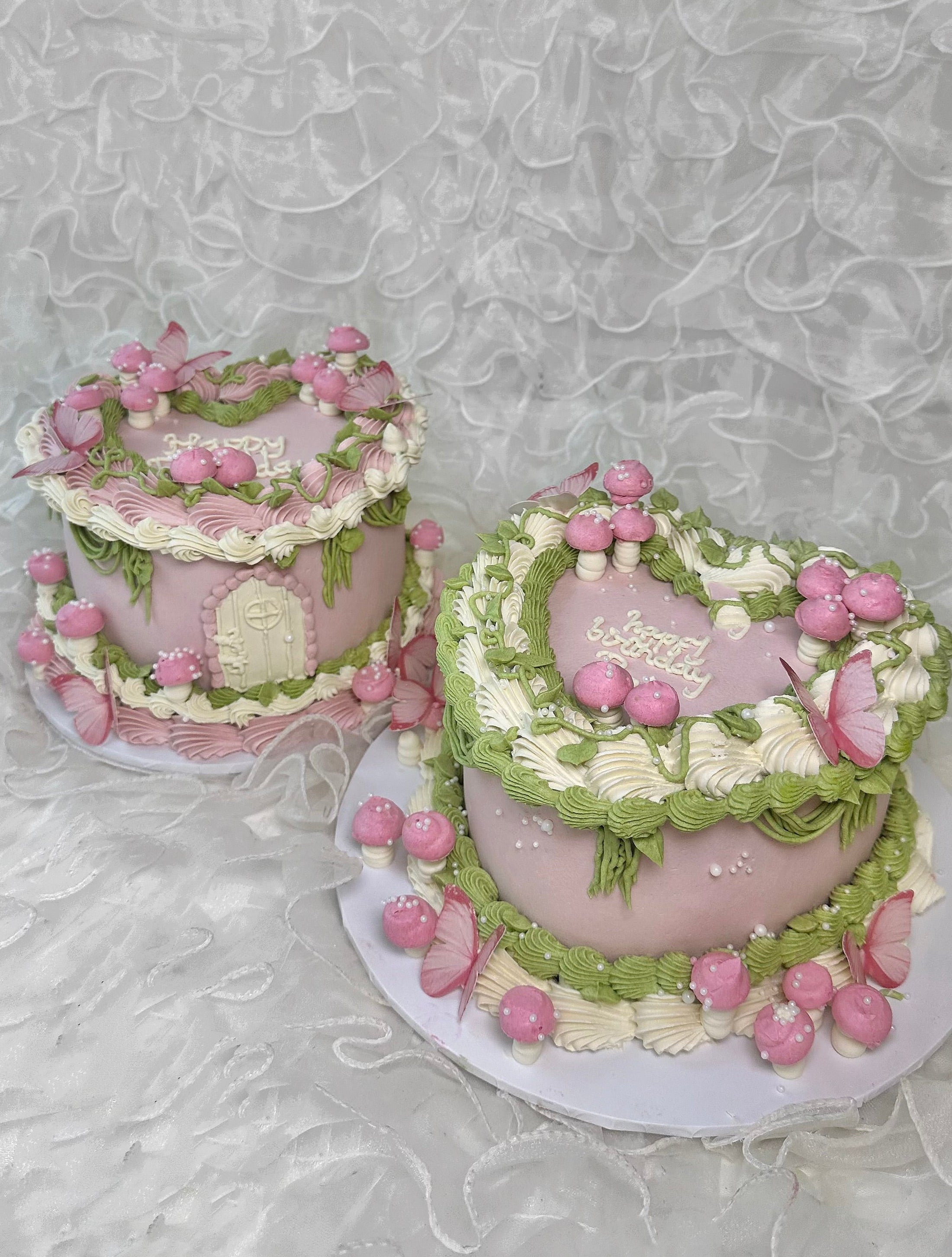 Two fairy garden cakes with pink and green icing and pink mushrooms 