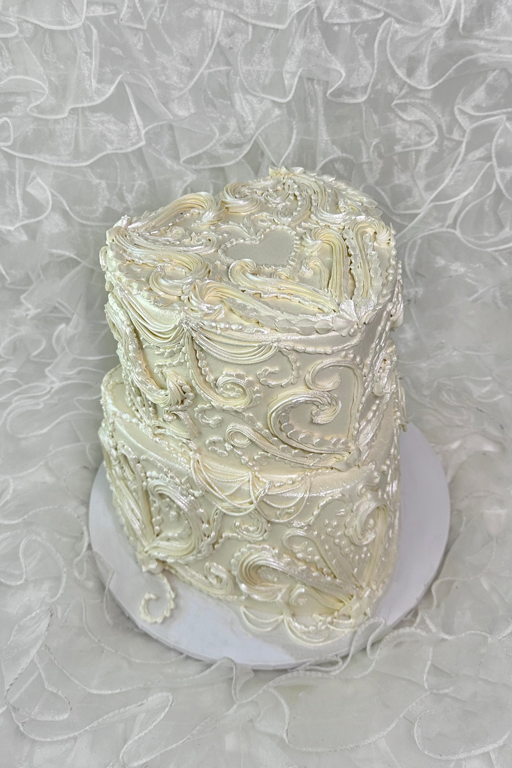 Two-tiered pearlescent cake with intricate white piping