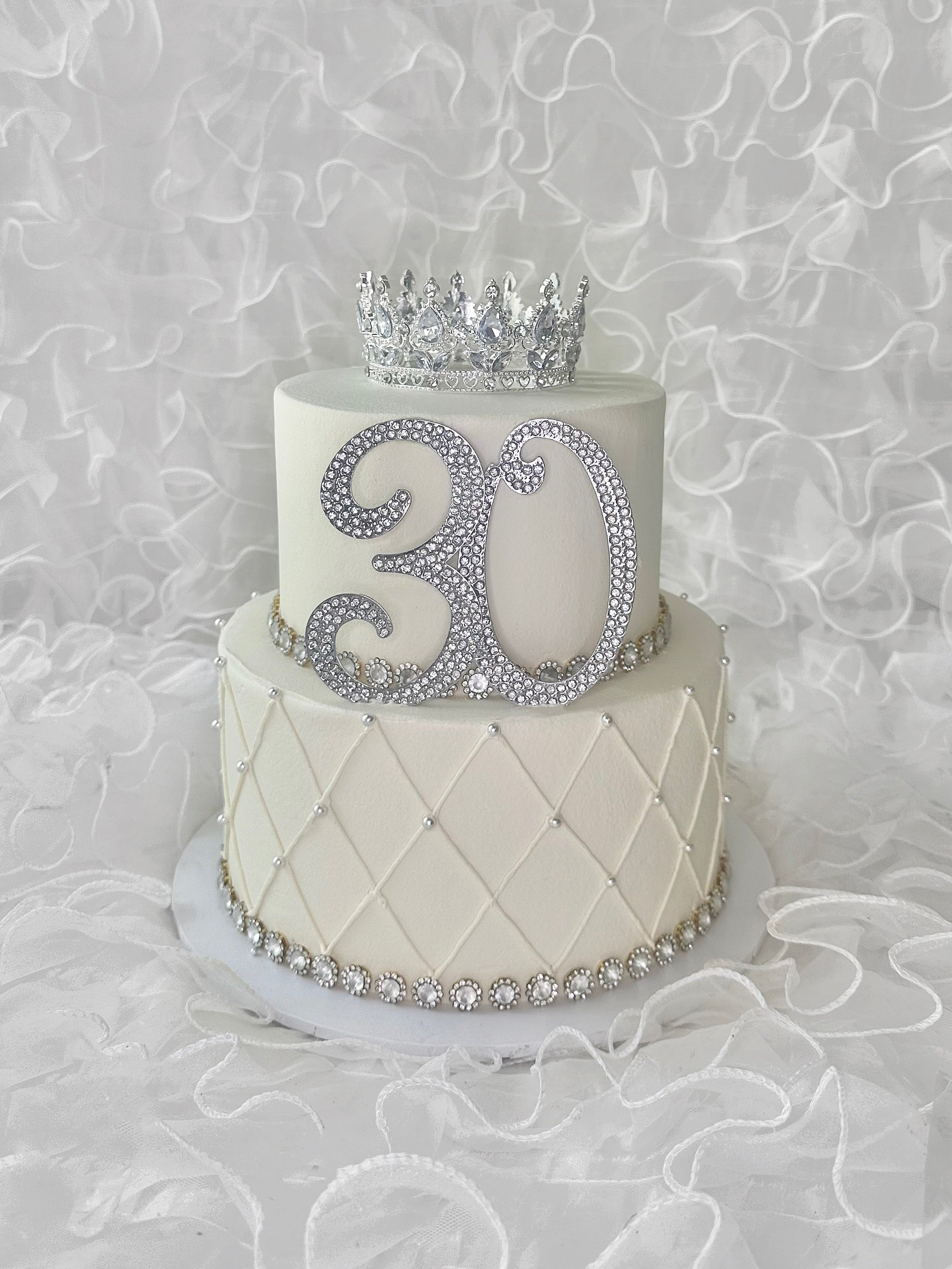 Two-tiered birthday cake with a silver number 30 and tiara 