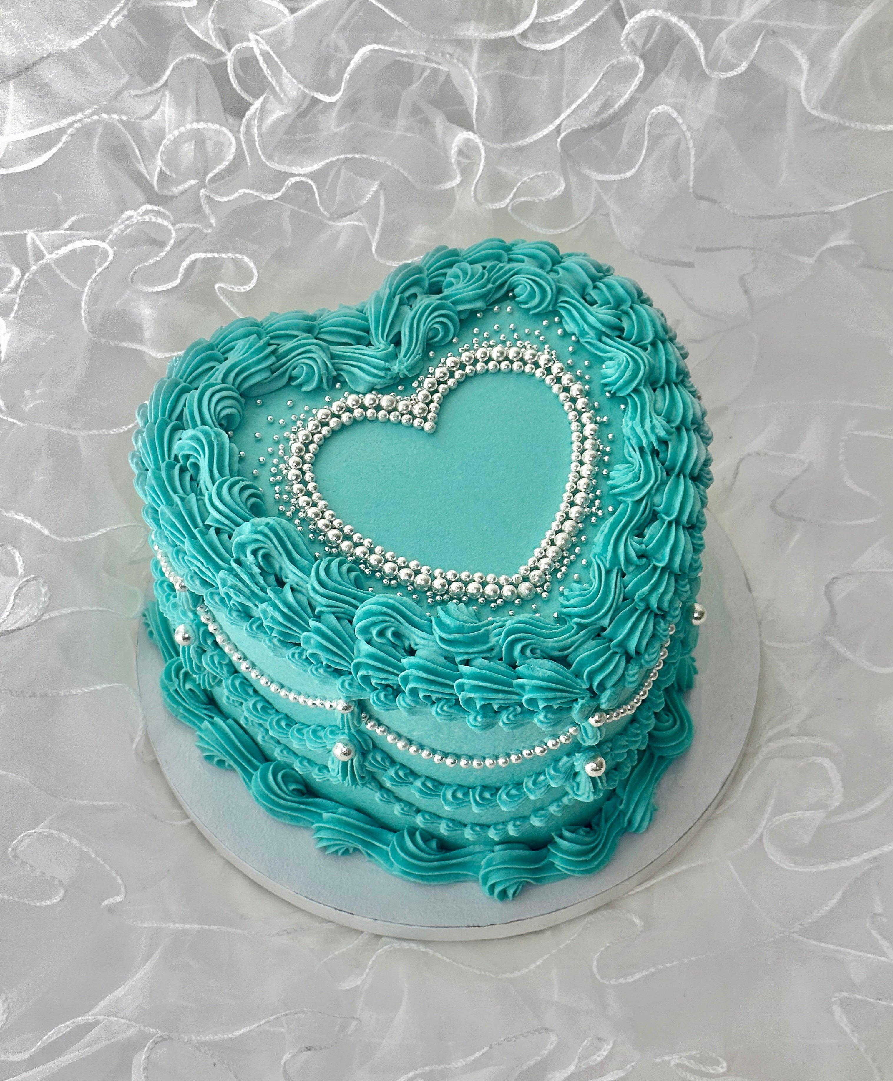 Turquoise heart-shaped cake with silver pearl heart detailing 