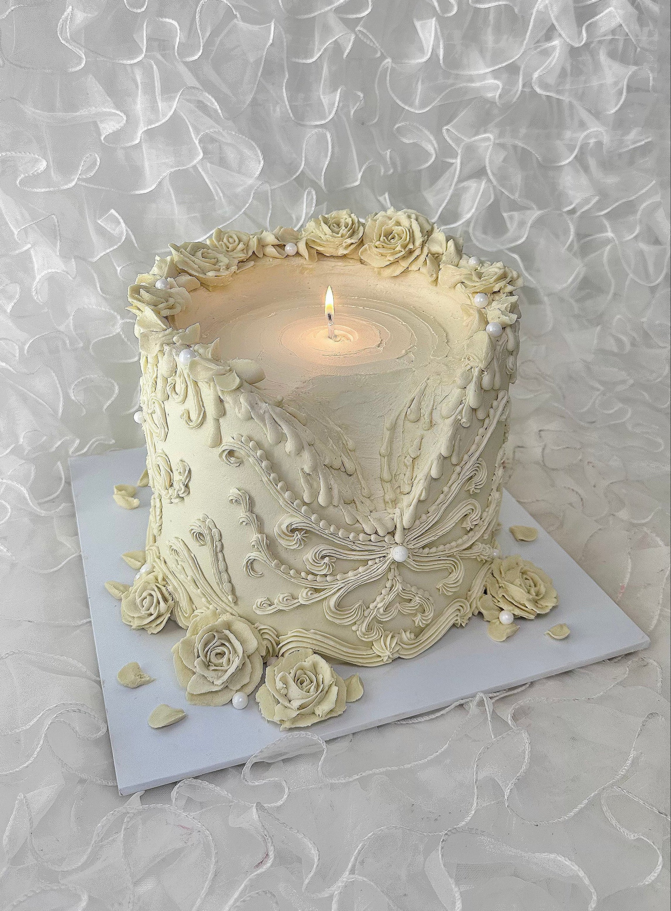 Ornate melting candle cake with rose detailing. 