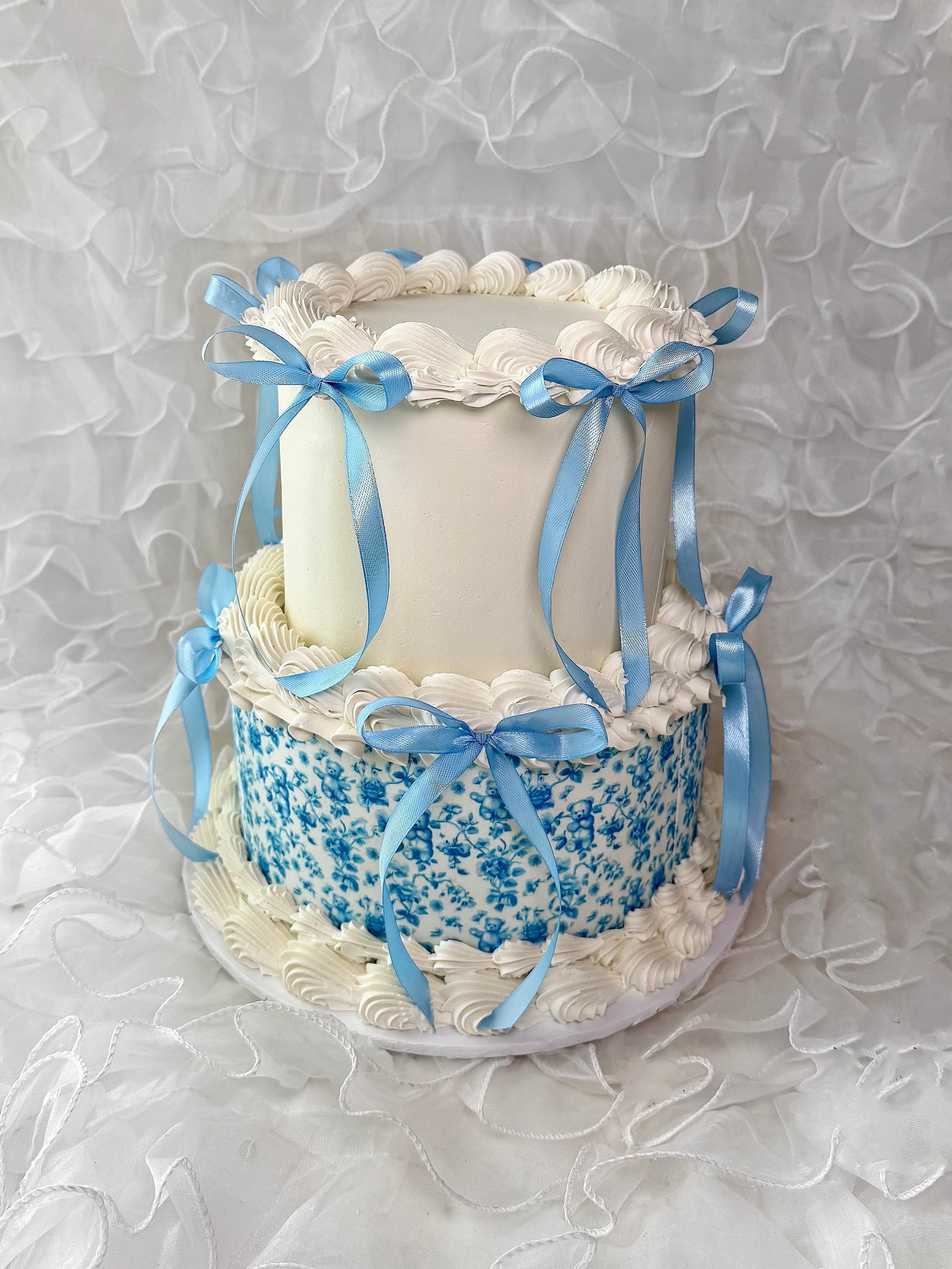 Baby shower cake with blue ribbons and blue floral detailing.