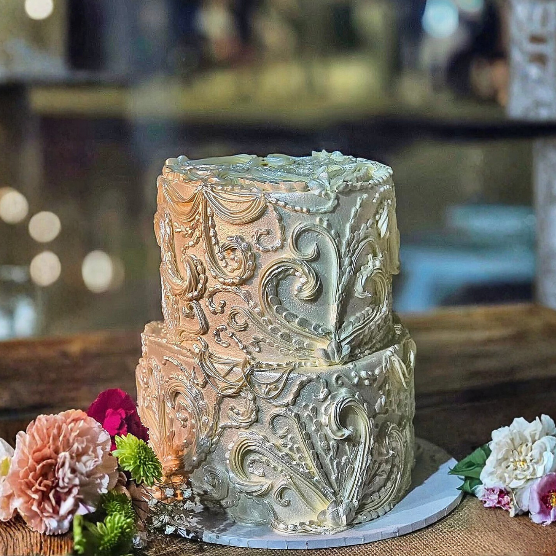 Decorative cake with intricate designs on a wooden table with flower - wedding cakes Sydney 