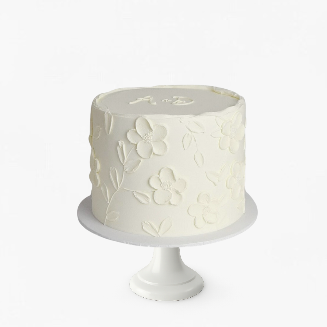 White cake with floral patterns on a white stand against a white background - gender reveal cakes Sydney 