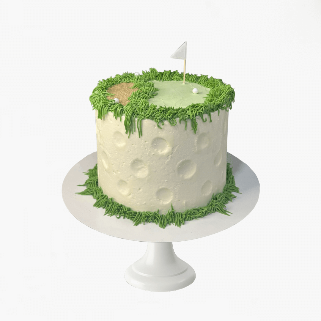 Golf-themed cake with green grass and a flag on a white stand - men's birthday cake 