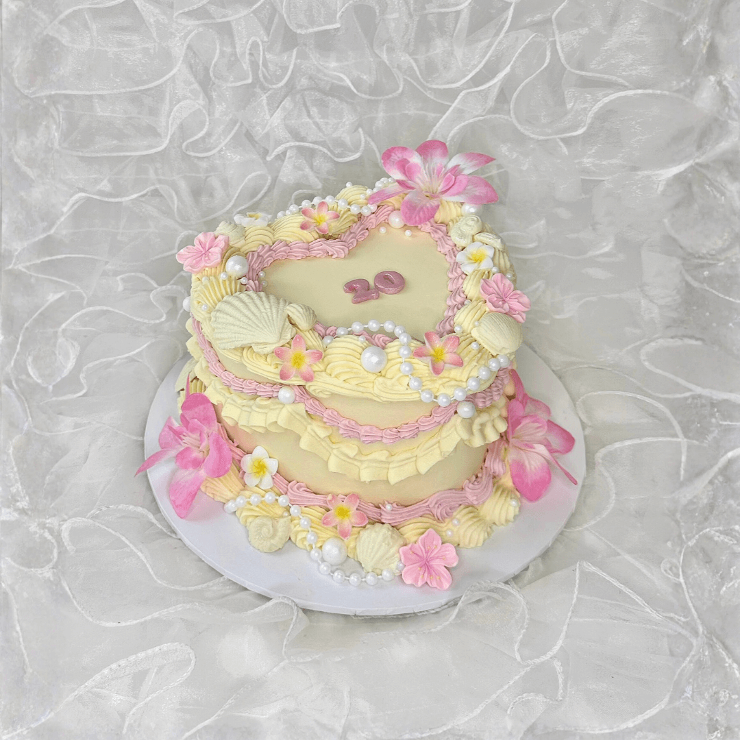 Decorative cake with pink and yellow flowers on a textured white background - custom birthday cakes