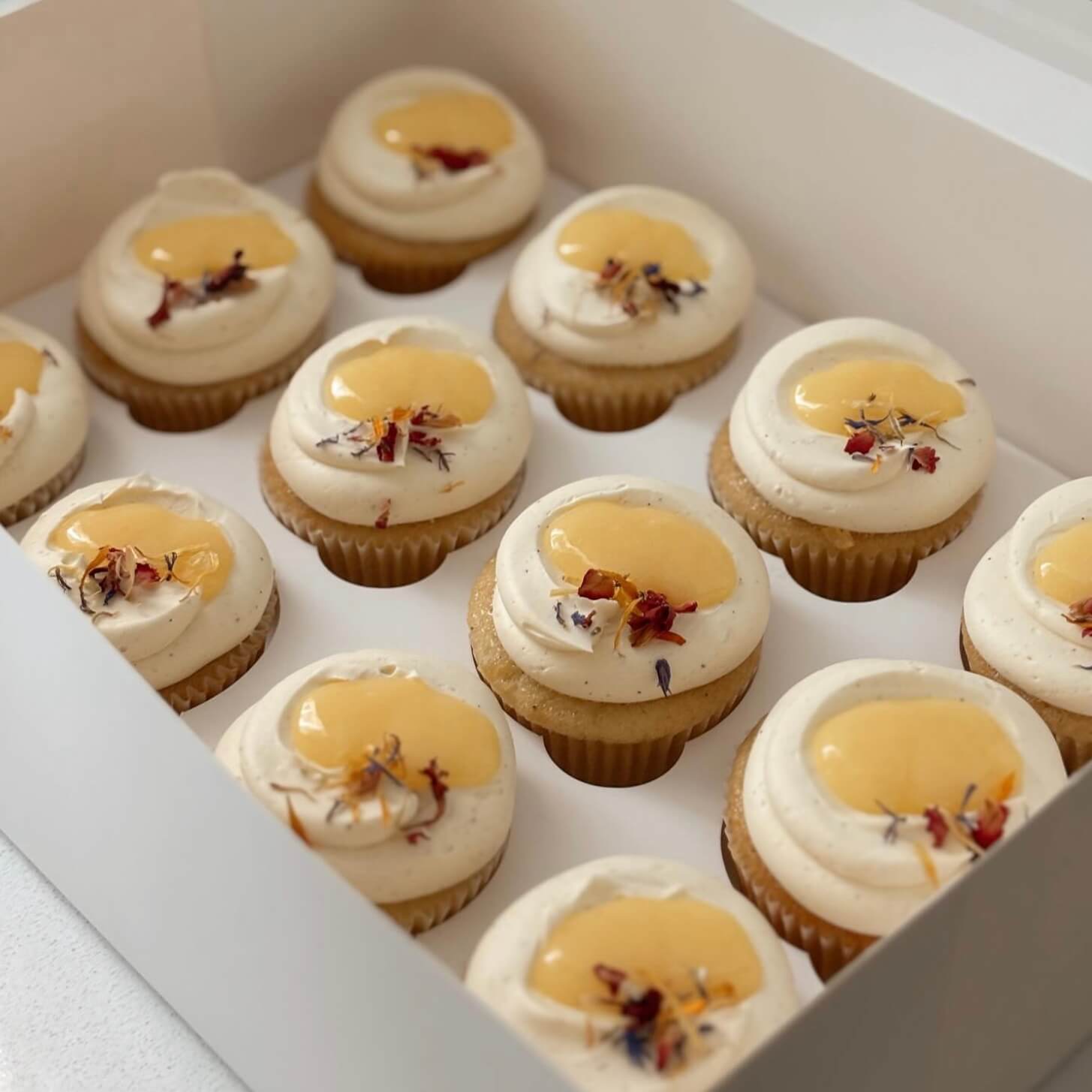 Cupcakes with white frosting and yellow filling in a box