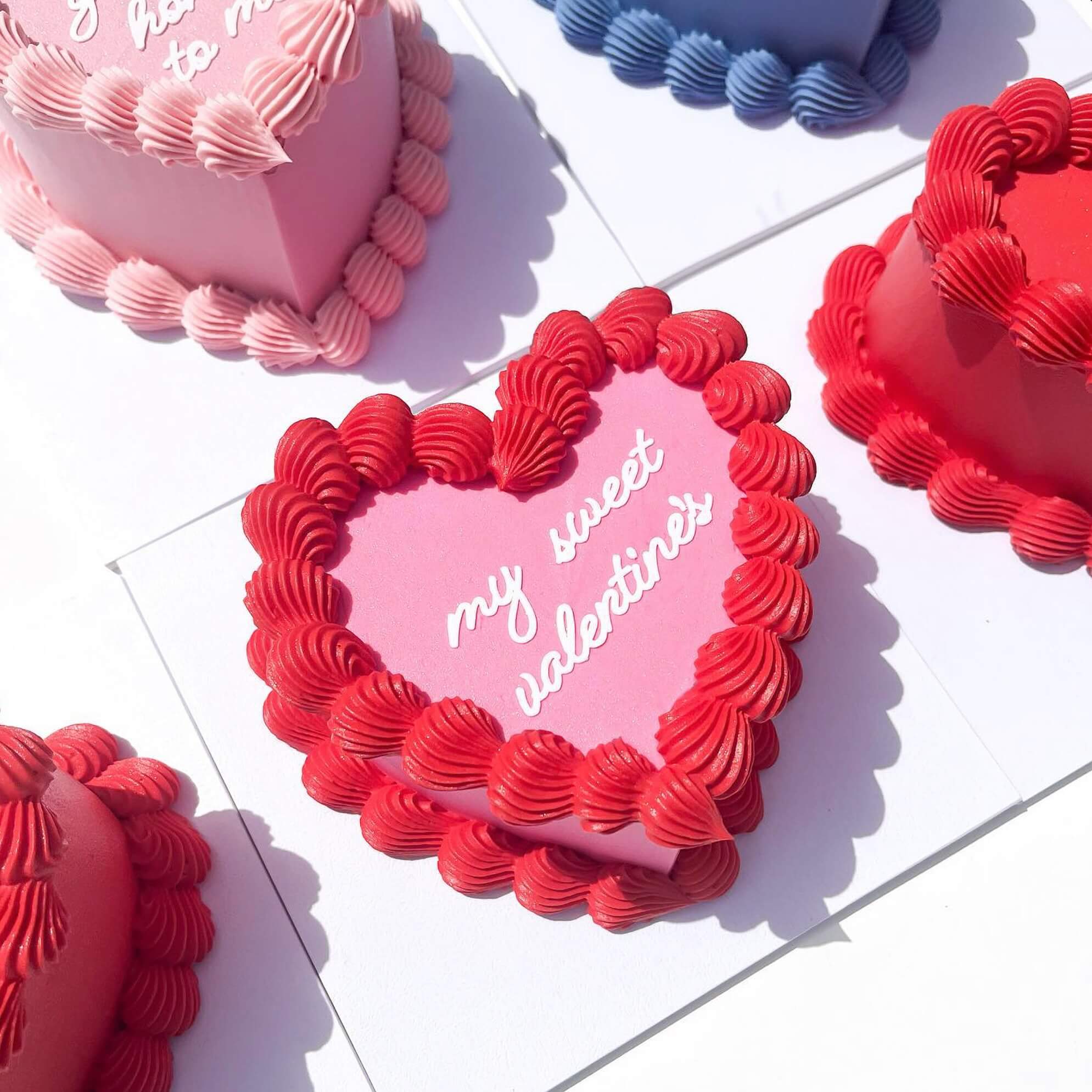 Heart-shaped Valentine's Day cake with red and pink frosting on a white background